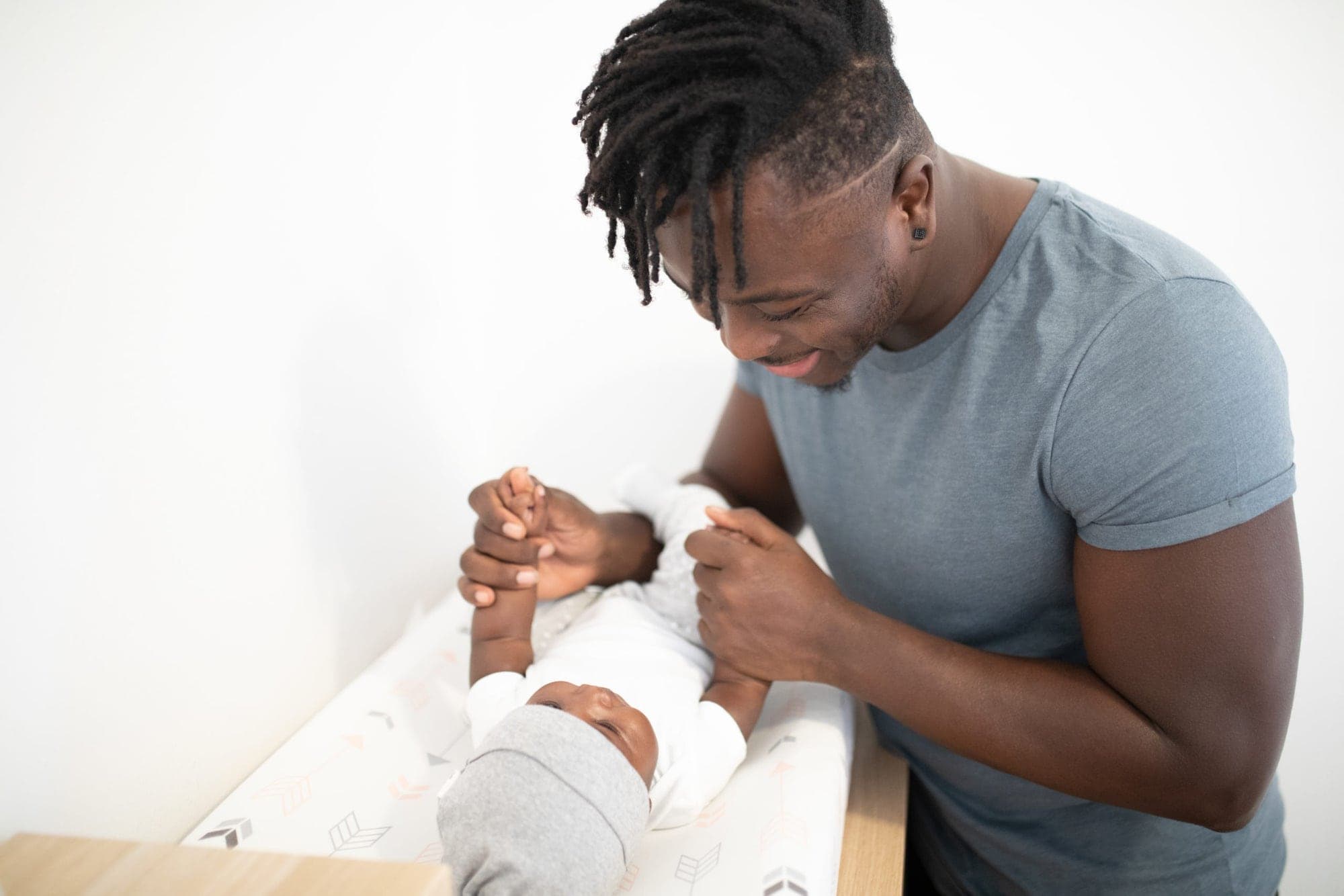 A father smiling down at his newborn on the changing table